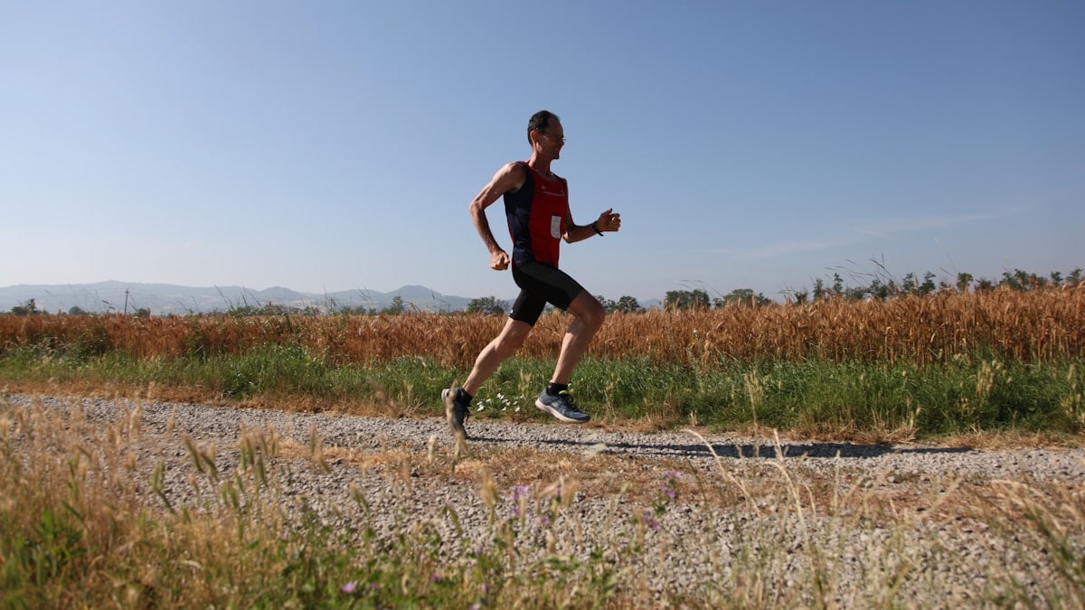 man red and black top running on farm road